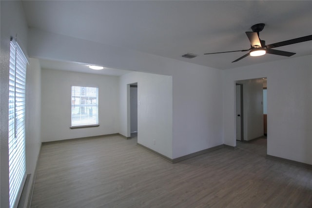 empty room with visible vents, ceiling fan, baseboards, and wood finished floors