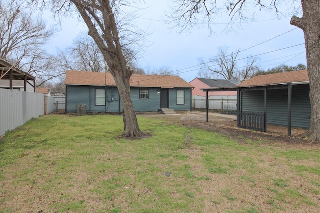 rear view of house with entry steps, a lawn, and fence