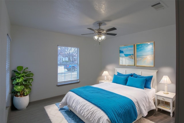 bedroom featuring a ceiling fan, baseboards, visible vents, and wood finished floors