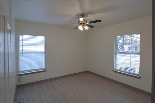 empty room featuring ceiling fan, baseboards, and wood finished floors