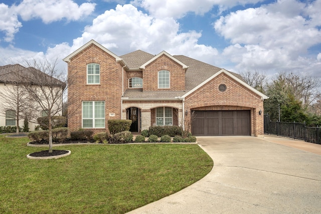 traditional home with brick siding, roof with shingles, fence, driveway, and a front lawn