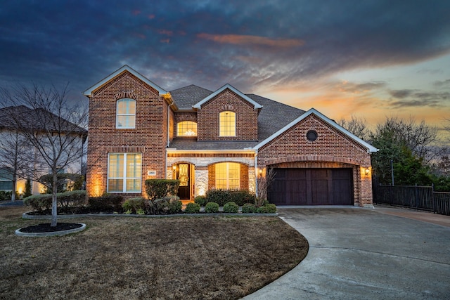 traditional home featuring brick siding, driveway, an attached garage, and roof with shingles