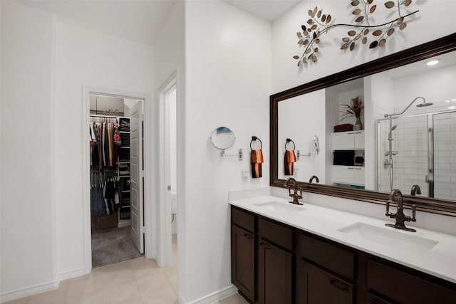 full bathroom featuring double vanity, a spacious closet, a sink, and a shower stall