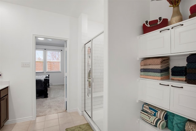 interior space featuring baseboards, ensuite bathroom, tile patterned flooring, vanity, and a shower stall