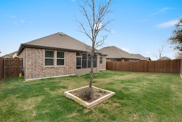 back of house with a yard, a fenced backyard, a shingled roof, and brick siding