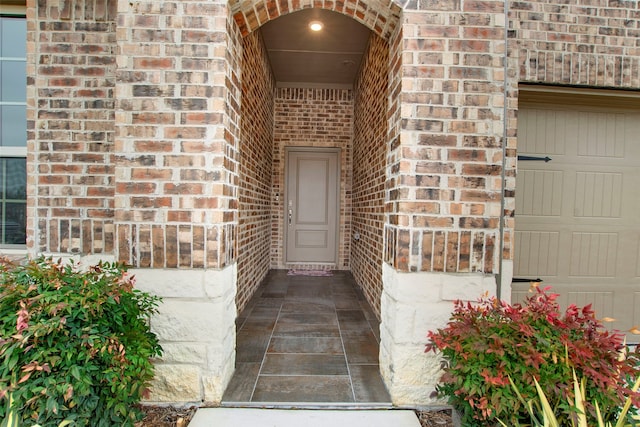 entrance to property featuring brick siding and an attached garage