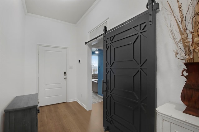 entrance foyer with a barn door, baseboards, crown molding, and wood finished floors