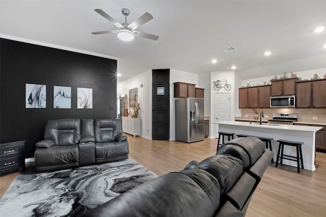 living room with recessed lighting, visible vents, light wood-style flooring, and baseboards