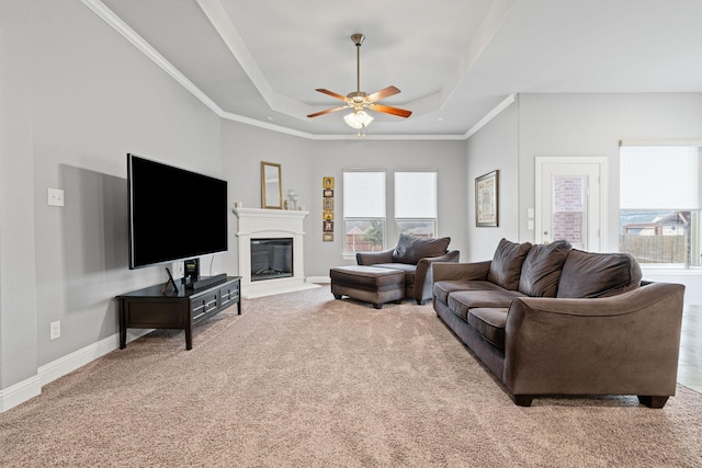 carpeted living room with a healthy amount of sunlight, baseboards, crown molding, and a tray ceiling