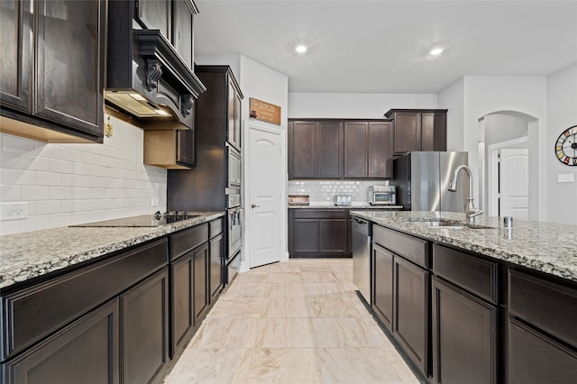 kitchen with marble finish floor, a sink, stainless steel appliances, light stone countertops, and dark brown cabinets