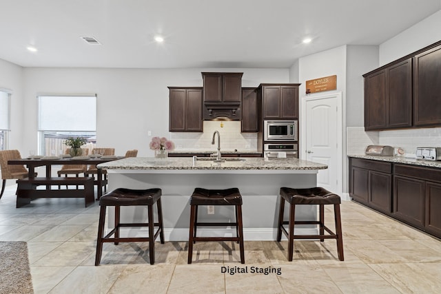 kitchen featuring a breakfast bar, visible vents, appliances with stainless steel finishes, and a sink