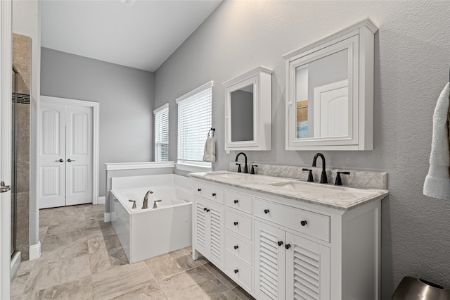 full bathroom with double vanity, a shower stall, a garden tub, and a sink