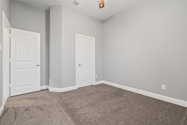 carpeted empty room featuring visible vents, a ceiling fan, and baseboards