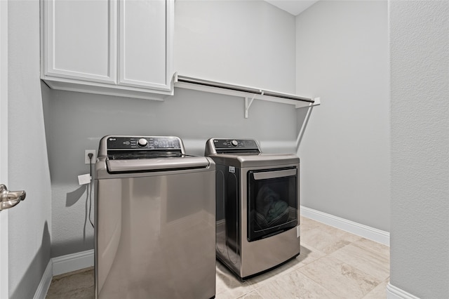 laundry room featuring washing machine and dryer, cabinet space, and baseboards