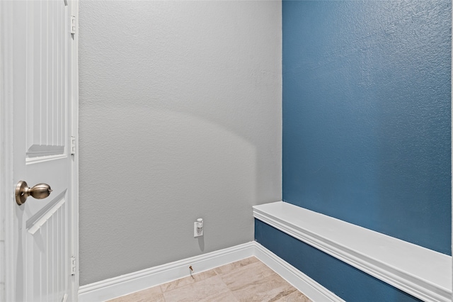 interior space with baseboards and a textured wall