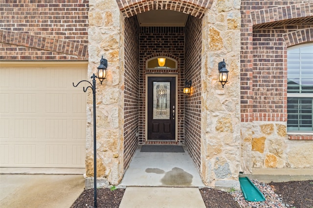 view of exterior entry featuring brick siding, stone siding, and an attached garage