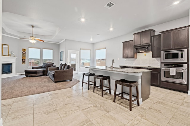 kitchen with visible vents, a sink, dark brown cabinetry, appliances with stainless steel finishes, and a kitchen bar