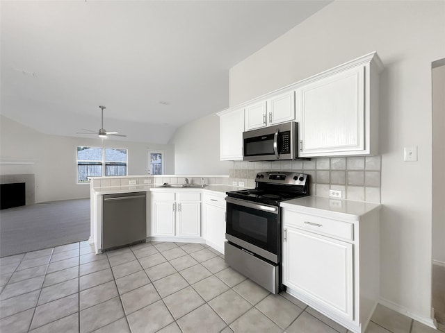 kitchen featuring a peninsula, white cabinets, light countertops, appliances with stainless steel finishes, and backsplash