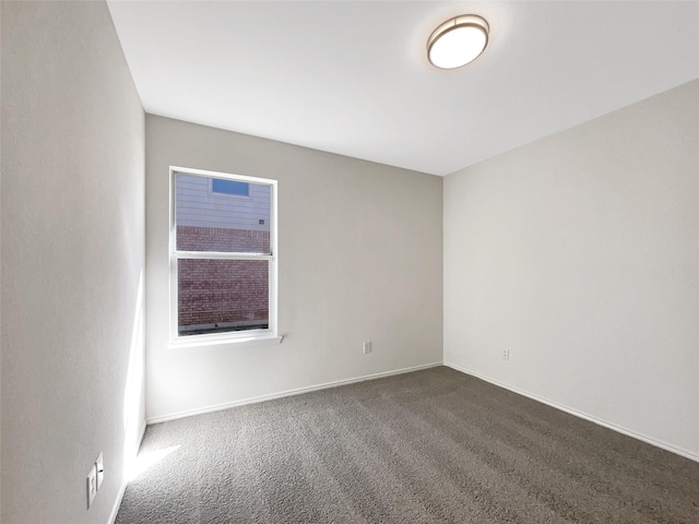 empty room featuring dark carpet and baseboards