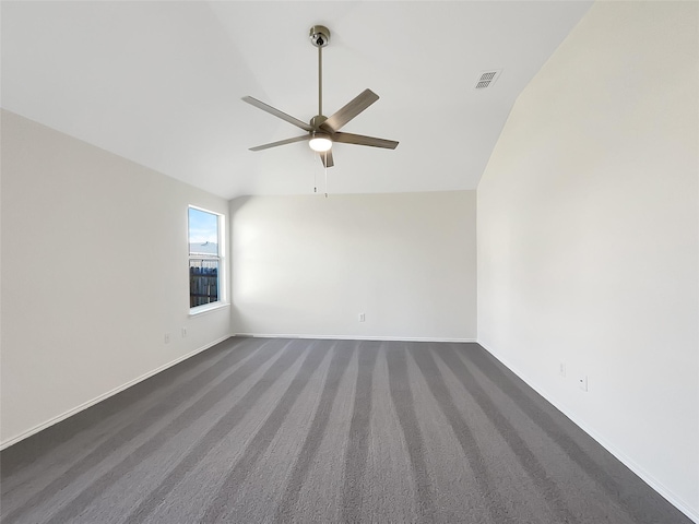 spare room featuring lofted ceiling, visible vents, dark carpet, ceiling fan, and baseboards