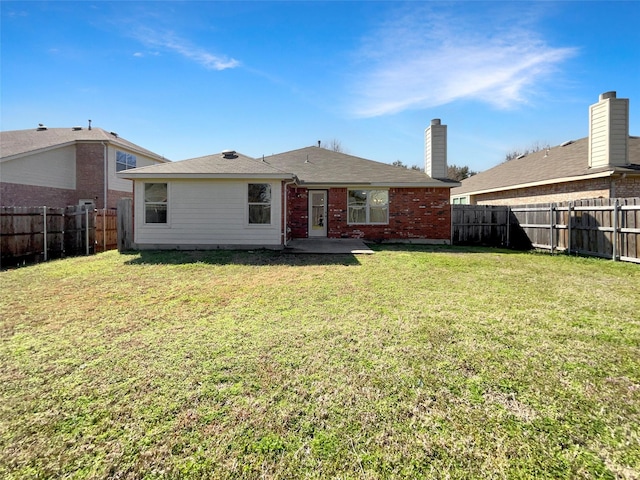 rear view of house featuring a yard, brick siding, a patio, and a fenced backyard