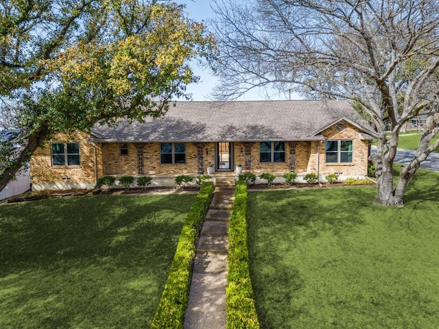 ranch-style house featuring brick siding, roof with shingles, and a front lawn