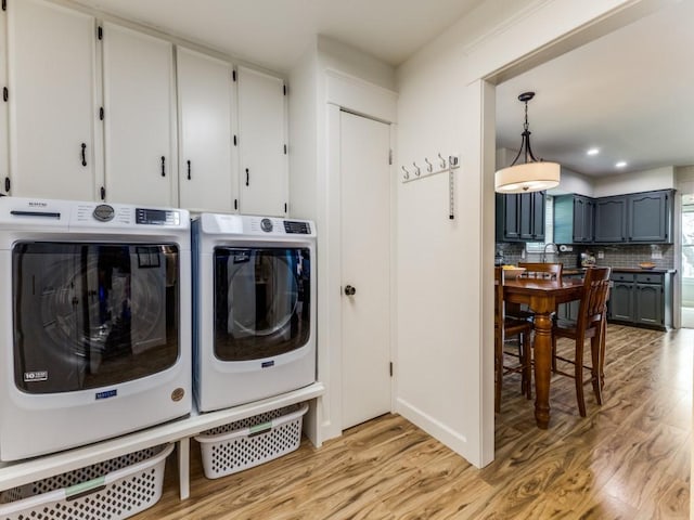 laundry room featuring recessed lighting, cabinet space, separate washer and dryer, and light wood finished floors