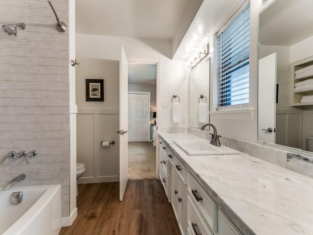 full bath with vanity, wood finished floors, a wainscoted wall, bathing tub / shower combination, and toilet