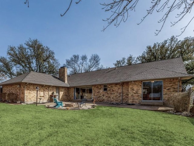 back of house featuring brick siding, roof with shingles, a chimney, a yard, and a patio