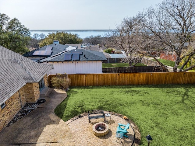 view of yard featuring a patio area, a water view, a fenced backyard, and an outdoor fire pit