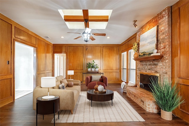 living area with dark wood-style flooring, a fireplace, visible vents, a decorative wall, and ceiling fan