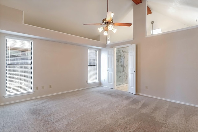 carpeted spare room with ceiling fan, high vaulted ceiling, and baseboards