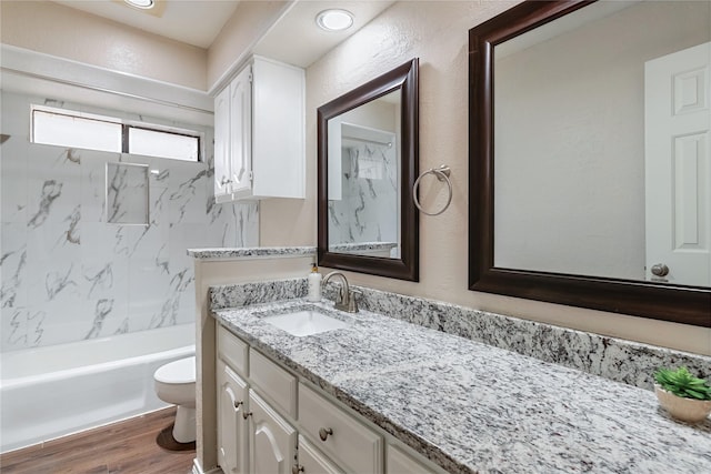 full bath featuring a textured wall, toilet, shower / bath combination, wood finished floors, and vanity