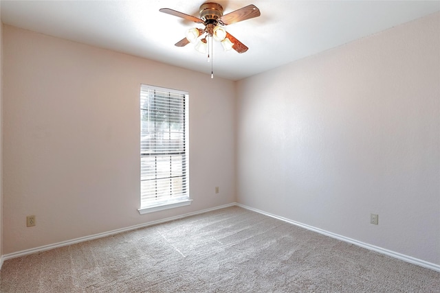 carpeted spare room featuring ceiling fan and baseboards