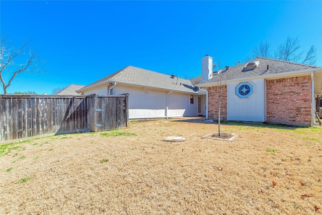 ranch-style house featuring brick siding, a chimney, fence, and a front yard