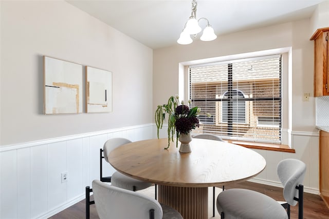 dining room with an inviting chandelier, dark wood-type flooring, and wainscoting