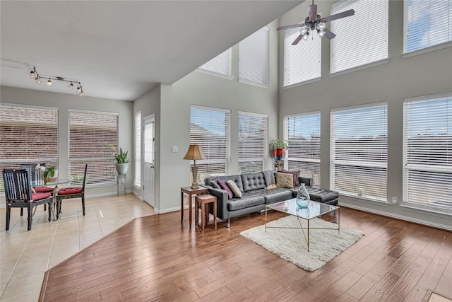 living area with ceiling fan, light wood finished floors, plenty of natural light, and baseboards