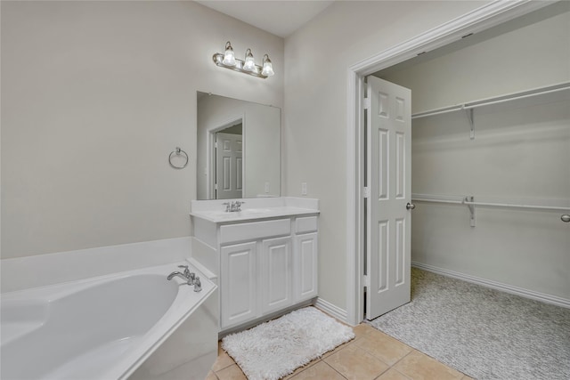 full bathroom featuring a garden tub, a spacious closet, vanity, baseboards, and tile patterned floors