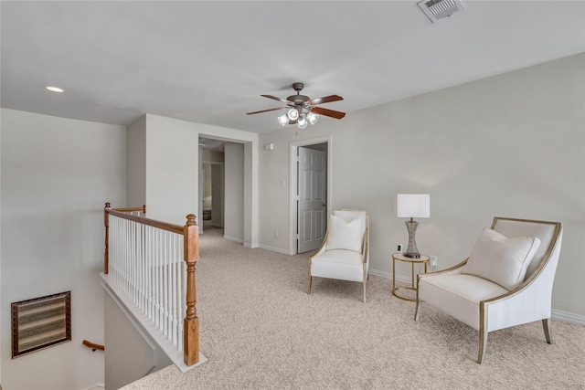 sitting room with a ceiling fan, an upstairs landing, visible vents, baseboards, and carpet