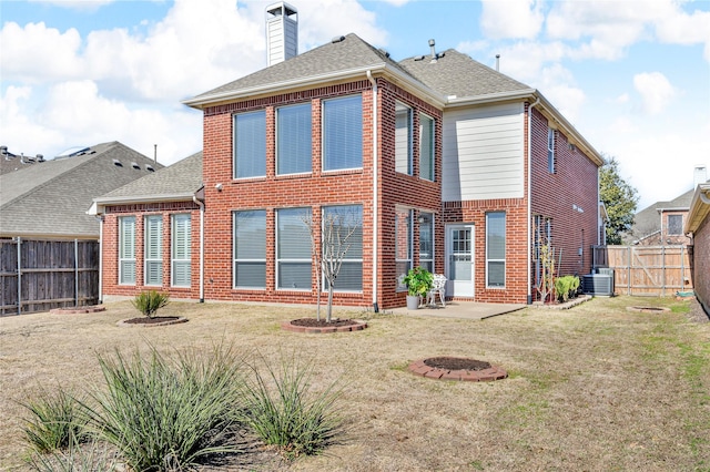 rear view of property featuring a shingled roof, a fenced backyard, a chimney, a yard, and brick siding