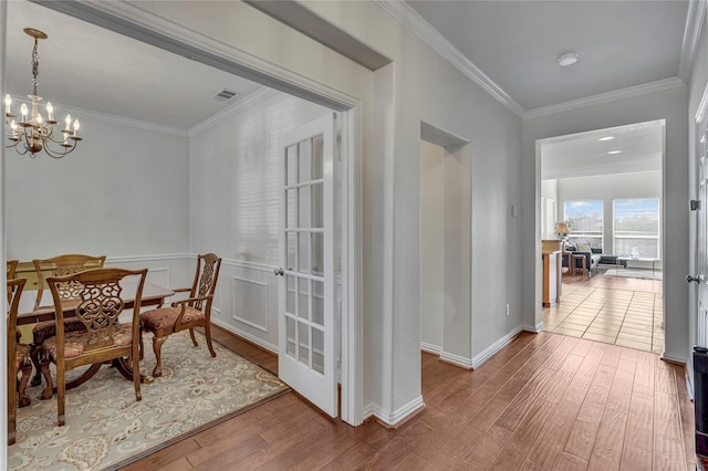 dining room featuring baseboards, visible vents, ornamental molding, wood finished floors, and a notable chandelier