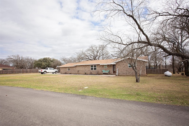 view of front of house with brick siding, a front yard, and fence