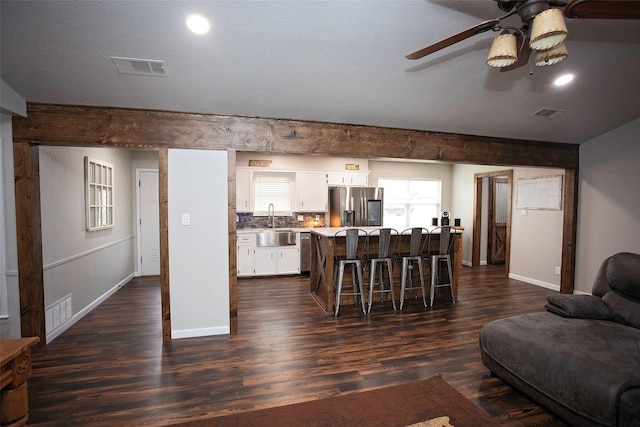 living area featuring dark wood-type flooring, visible vents, and baseboards