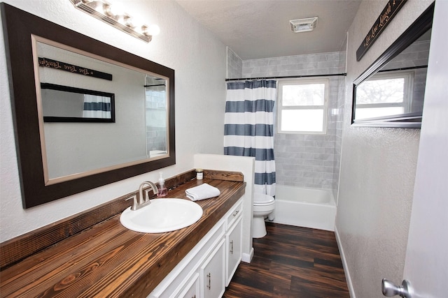 full bath with a textured ceiling, toilet, wood finished floors, vanity, and shower / bathtub combination with curtain