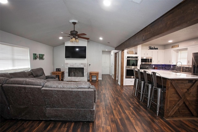 living room with plenty of natural light, dark wood finished floors, vaulted ceiling, and a fireplace