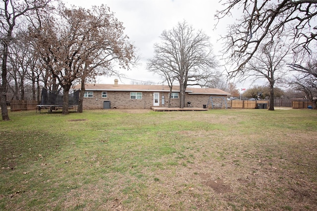 view of yard featuring a deck, a trampoline, a fenced backyard, and central air condition unit