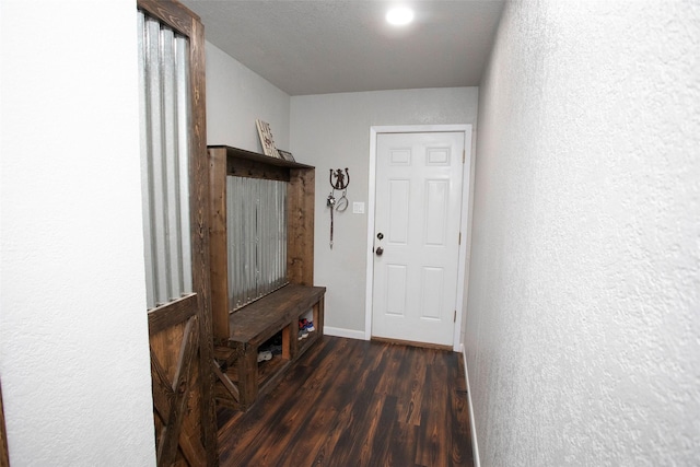 mudroom featuring baseboards, dark wood finished floors, and a textured wall