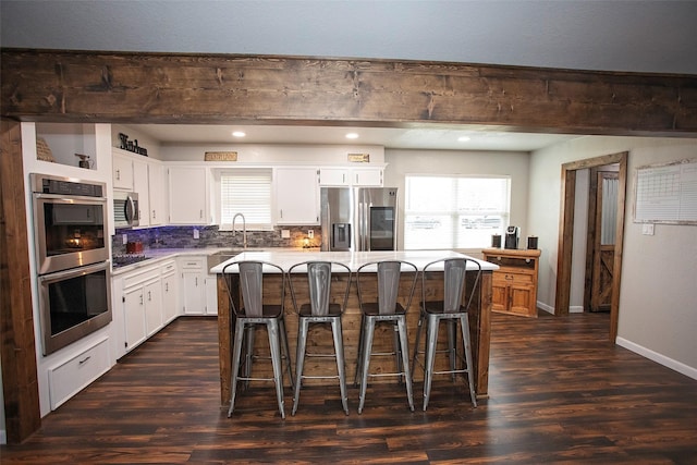 kitchen featuring a healthy amount of sunlight, appliances with stainless steel finishes, dark wood finished floors, and light countertops