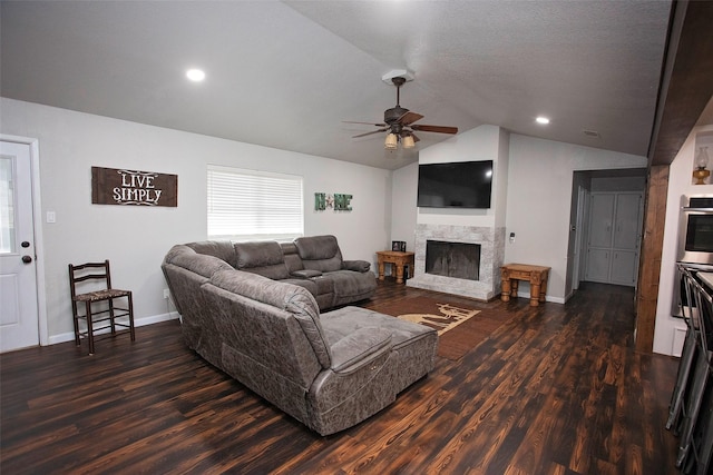 living room featuring lofted ceiling, a ceiling fan, wood finished floors, and a stone fireplace