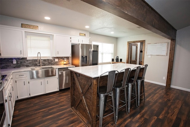 kitchen with appliances with stainless steel finishes, dark wood-style flooring, a sink, and decorative backsplash